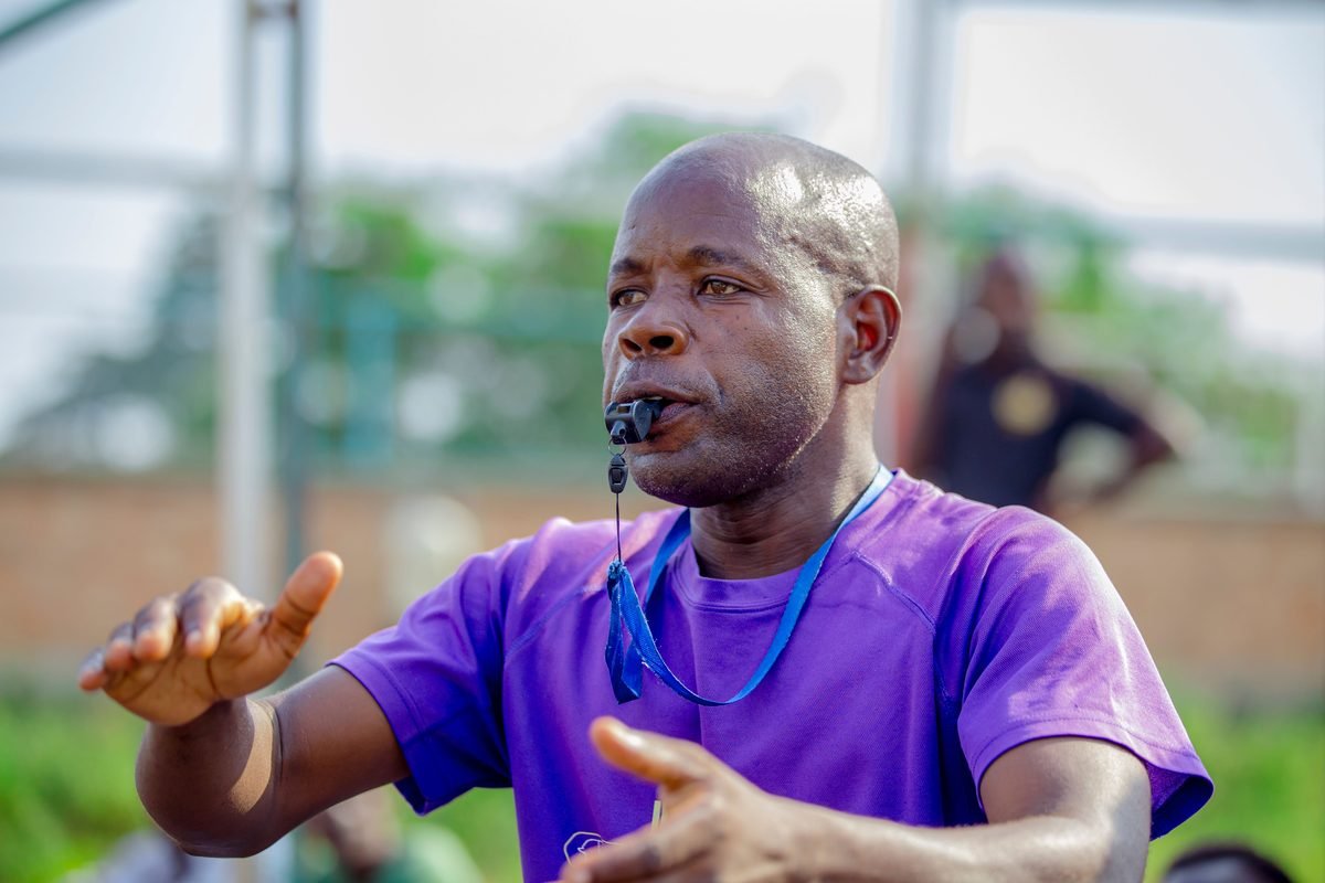 A coach with a whistle explaining a drill outdoors