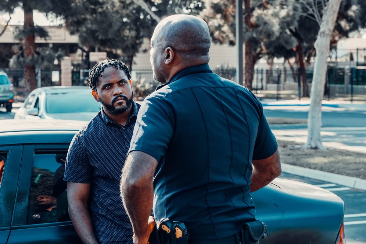A police officer speaking one to one with a man beside a car