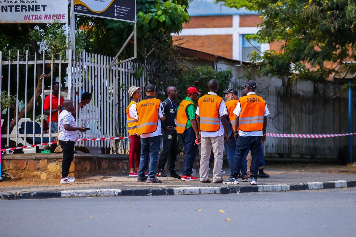 Safety stewards in high-visibility vests gathered at a gate