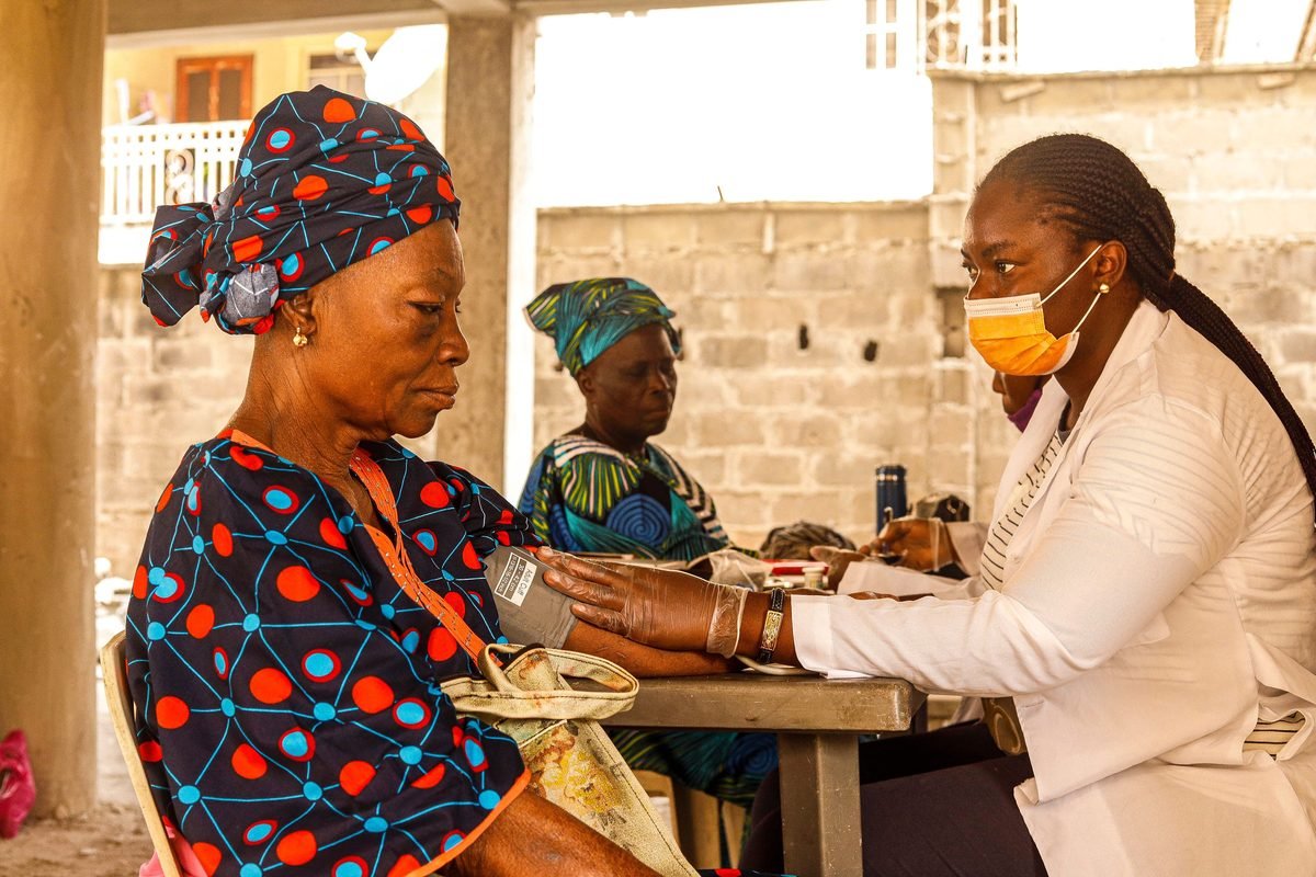 A health worker checking the blood pressure of an older woman