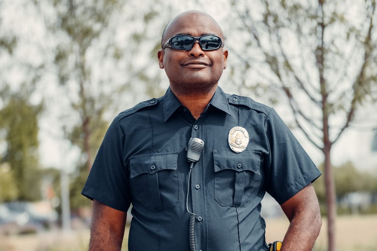 A private security officer in uniform with a radio, standing outdoors