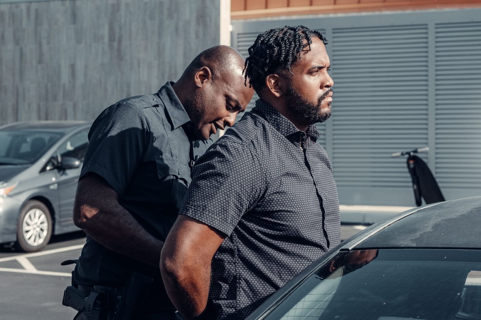 A police officer escorting a handcuffed man to a vehicle with a calm escort hold
